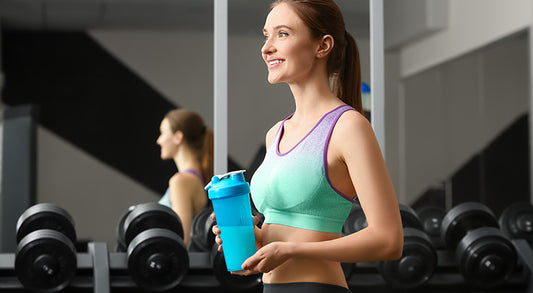 Athletic young woman with protein shake in gym